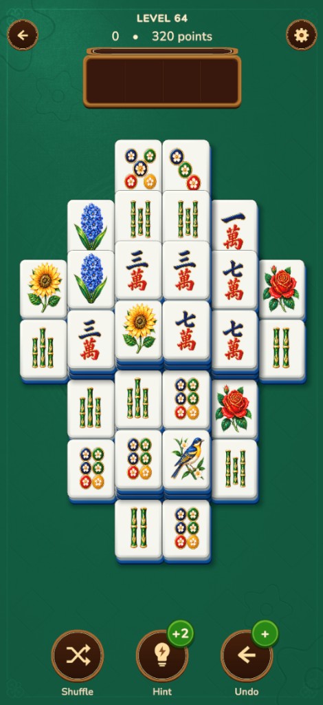 Mahjong gameplay: stacked botanical tiles on a deep green table